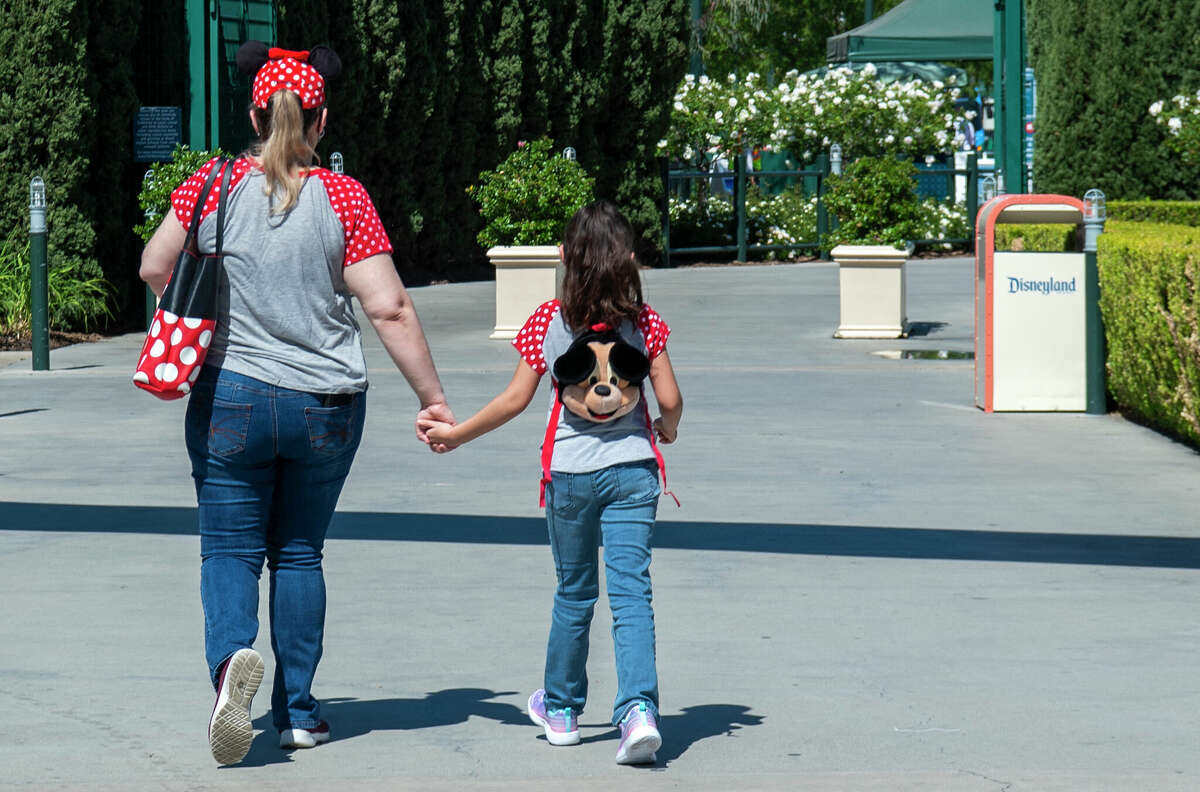 Visitors wearing Mickey ears enter Disneyland on the day of the park's re-opening on April 30, 2021, in Anaheim, California. 
