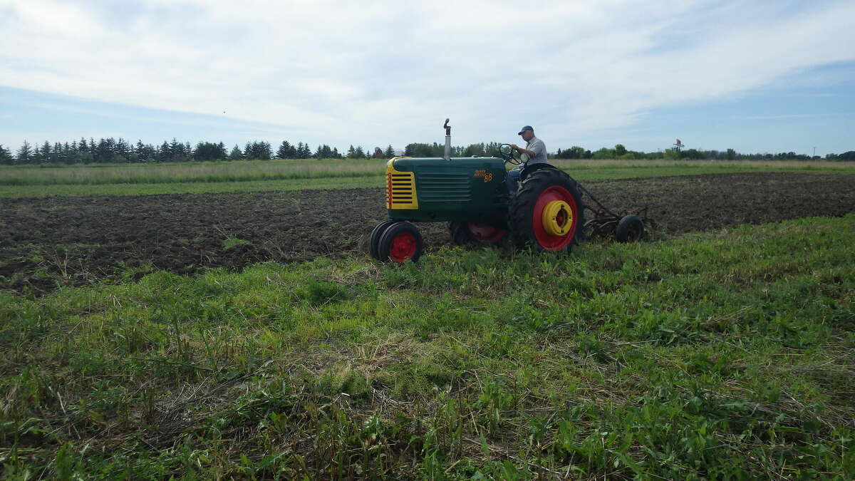 Tom Lounsbury plows with his newly refurbished vintage 1953 Oliver tractor, pulling a more vintage, and rusty, two-bottom Massey-Harris plow. The plow is slated for an original-color paint job as well.