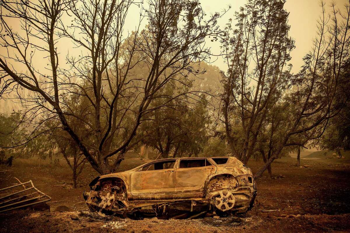 A scorched vehicle rests sits next to a driveway as the McKinney Fire burns in Klamath National Forest, Calif., on Sunday, July 31, 2022.