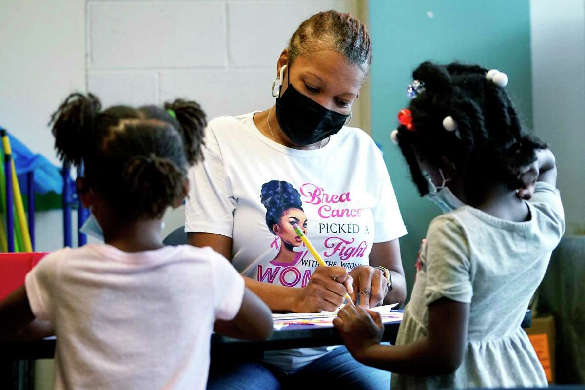 Laiah Collins, 4, left, and Charisma Edwards, 5, right, work with Davetra Richardson (STLS) in a classroom at Chalmers Elementary school in Chicago, Wednesday, July 13, 2022. America's big cities are seeing their schools shrink, with more and more of their schools serving small numbers of students. Those small schools are expensive to run and often still can't offer everything students need (now more than ever), like nurses and music programs. Chicago and New York City are among the places that have spent COVID relief money to keep schools open, prioritizing stability for students and families. But that has come with tradeoffs. And as federal funds dry up and enrollment falls, it may not be enough to prevent districts from closing schools. (AP Photo/Nam Y. Huh)