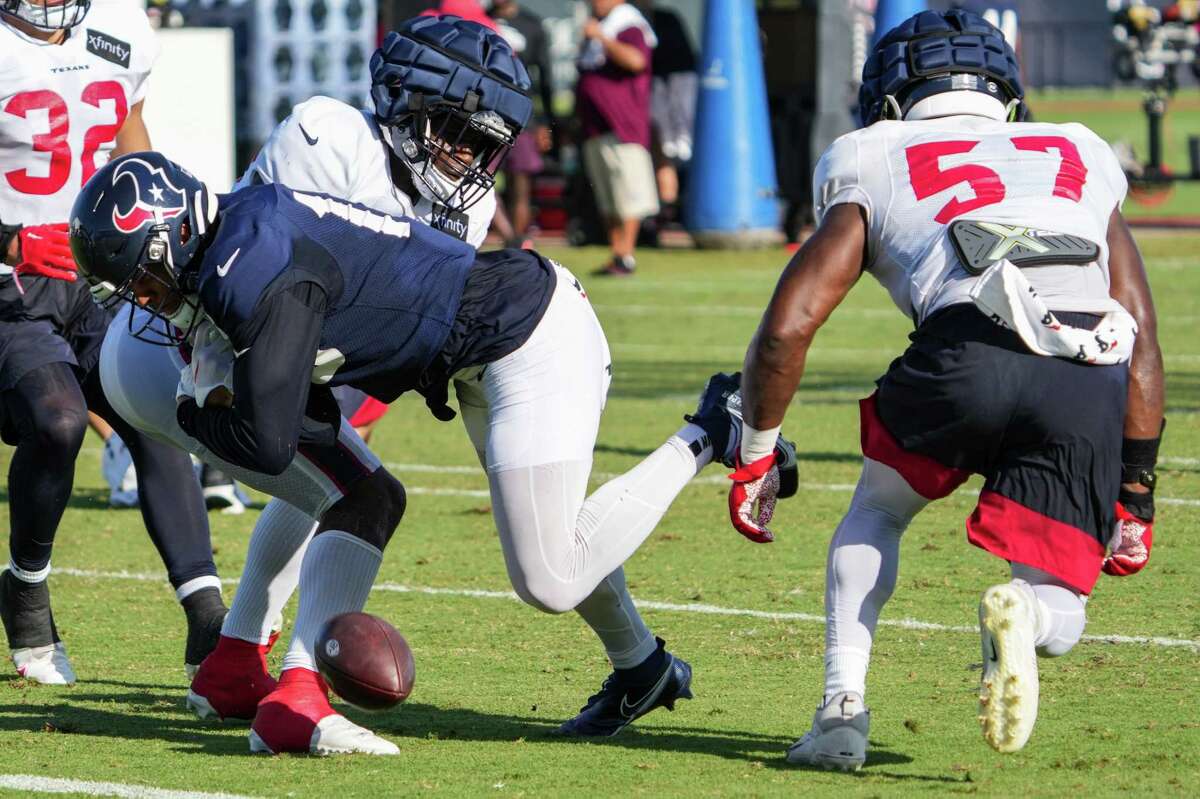 Houston Texans wide receiver Chris Moore (15) fumbles as he is hit by linebacker Neville Hewitt during an NFL training camp Tuesday, Aug. 2, 2022, in Houston.