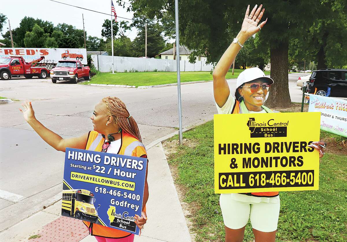 Tammy Brookfield, left, and Crystal Killion, right, monitors with Illinois Central School Bus, were working recently in front of James H. Killion Park on Washington Avenue to attract people who may be interested in becoming bus drivers. The company is offering a $22 an hour starting salary. Illinois Central operates buses for the Alton School District from its North Alby Street garage.