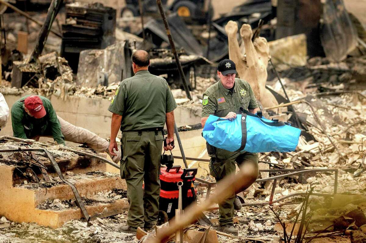 Sheriff's Deputy Michael Johnson carries the remains of a McKinney Fire victim from a destroyed home in Klamath National Forest. So far, three others have been found dead.