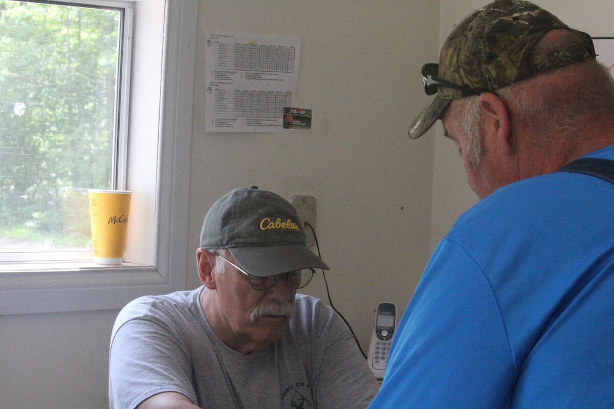 Mecosta County Rod & Gun Club president Randy Rice (left) signs in Mark Curtiss for Saturday's sporting clays shoot.