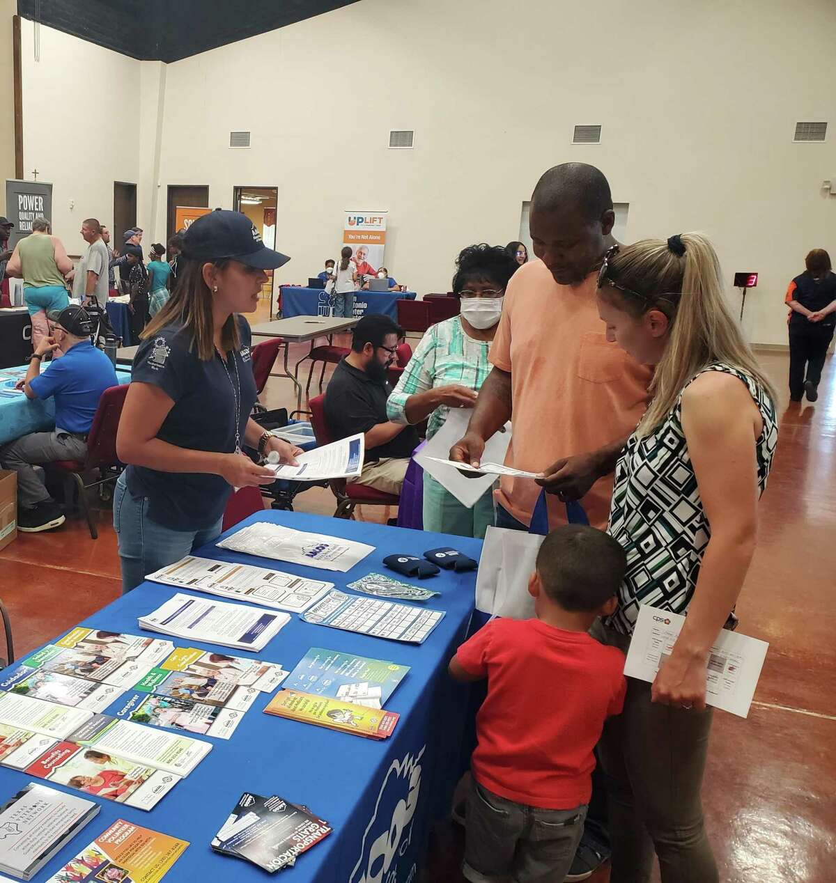 Alondra Sanches, left, Alamo Area Council of Governments outreach specialist, reviews pamphlets with program fair attendees San Antonio residents Aaron and Elena Belleastin, and their 3-year-old son, Phillip.