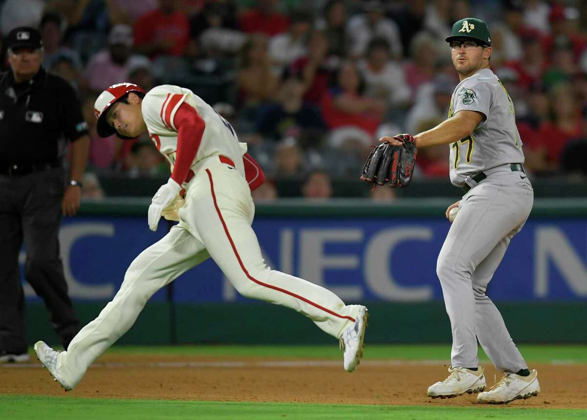ANAHEIM, CA - AUGUST 02: Shohei Ohtani #17 of the Los Angeles Angels ducks under Jonah Bride #77 of the Oakland Athletics at third base on a ground out by Luis Rengifo in the fifth inning at Angel Stadium of Anaheim on August 2, 2022 in Anaheim, California. (Photo by John McCoy/Getty Images)