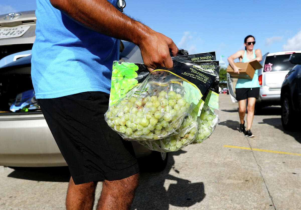 Volunteers distribute food, including fresh grapes, into cars during a food distribution from the Houston Food Bank at Trader’s Village on Wednesday, July 20, 2022 in Houston. According to officials, almost. 1000 cars showed up to the giveaway, some lining up as early as 6am.