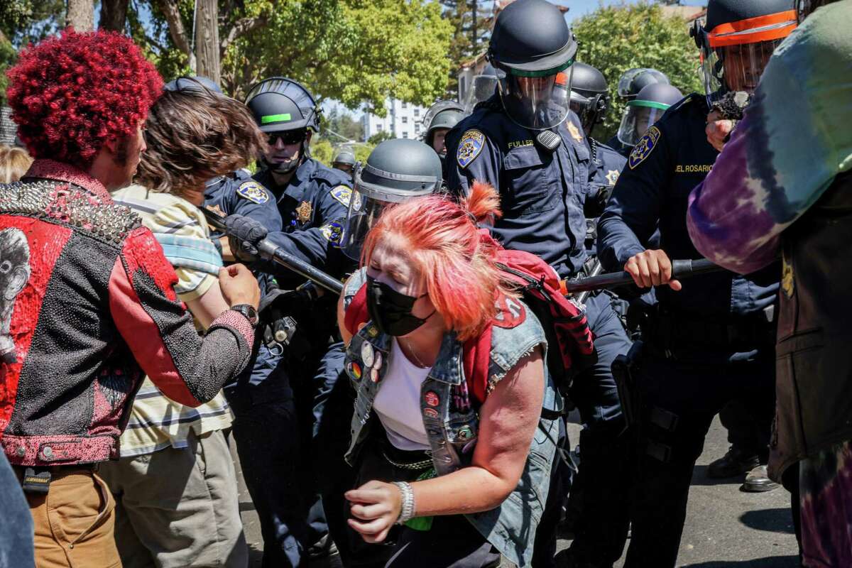 A protester winces in pain as police attempt to prevent the crowd from entering People’s Park in Berkeley, Calif. on Wednesday, Aug. 3, 2022. Protesters gathered to decry the clearing out of the park in preparation for the development of student housing.
