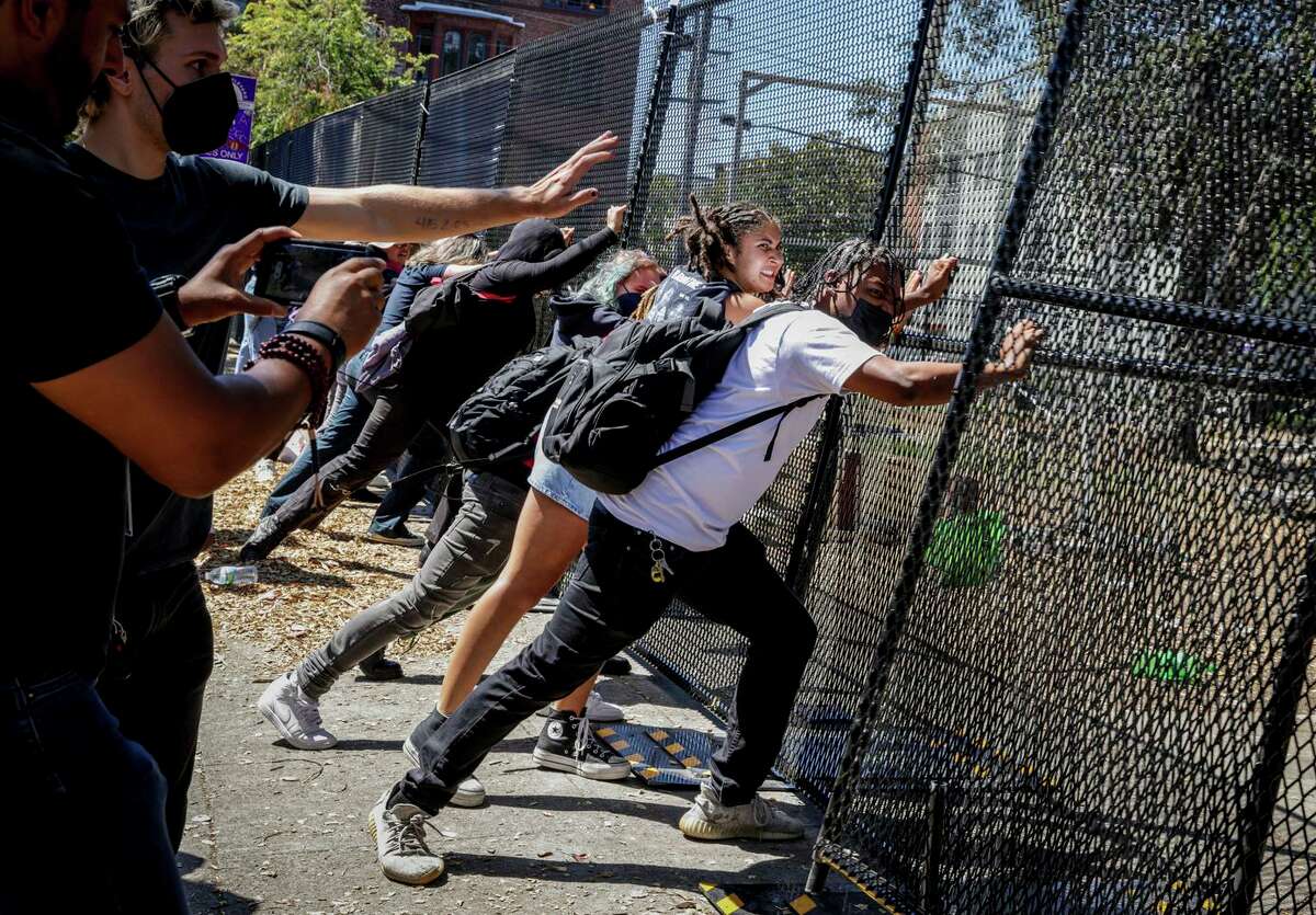Protesters try to break down a gate surrounding People's Park in Berkeley, Calif., on Wednesday, August 3, 2022. Protesters gathered to denounce the cleanup of the park in preparation for student housing development.