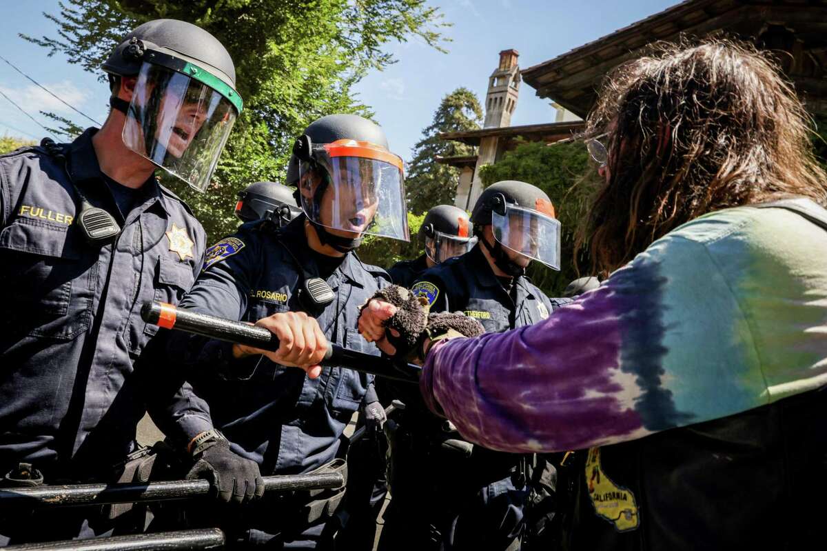 Joint caption Above: Police create a barrier between protesters and access to People’s Park in Berkeley, Calif. on Wednesday, Aug. 3, 2022. Protesters gathered to decry the clearing out of the park in preparation for the development of student housing. Below: Naya Rose cries out after being arrested at People’s Park in Berkeley, Calif. on Wednesday, Aug. 3, 2022.