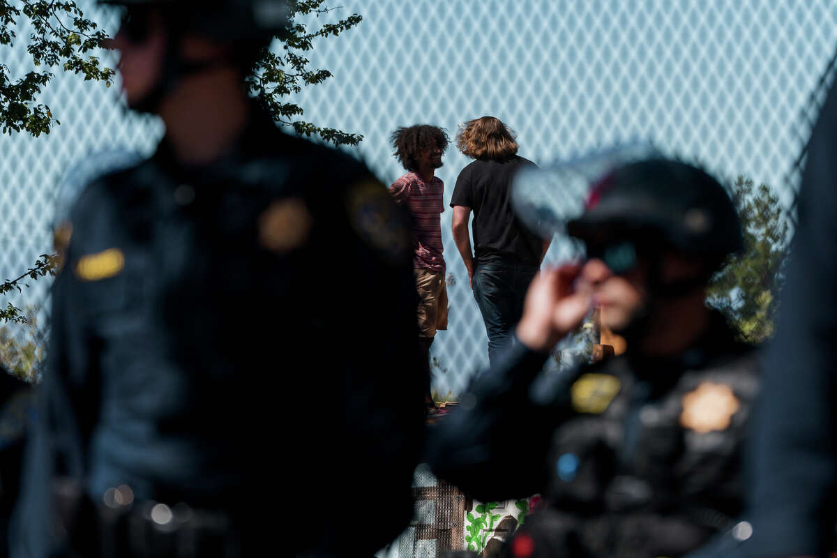 Protesters talk to each other as California State Highway Patrol officers police at a protest at People's Park in Berkeley, Calif., on Wednesday, Aug. 3.  3, 2022.