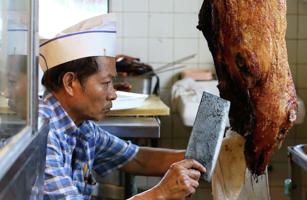 Cho Woo cuts roast pork for a lunch customer one day before Long Sing BBQ is set to close its doors on July 26, 2017, in Houston.
