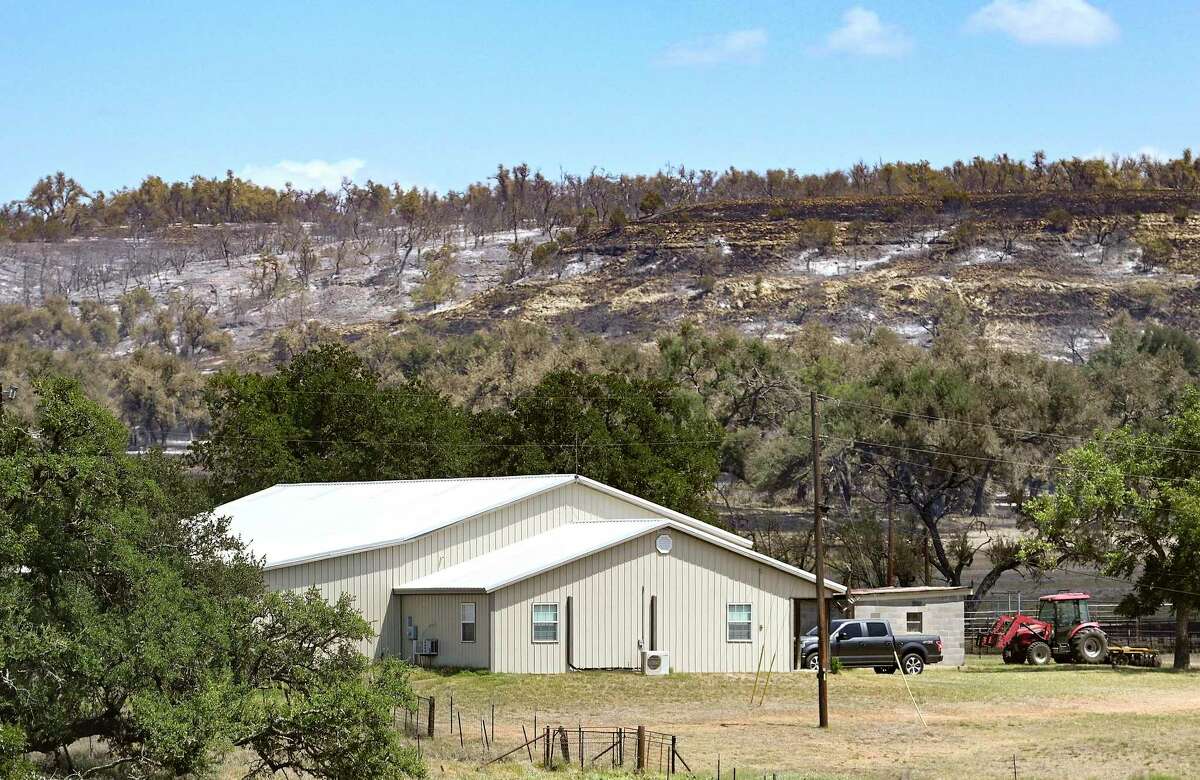 A charred hill, burned by the Big Sky Fire, overlooks a home in the Hill Country. Fire crews from Gillespie, Kendall, Llano counties and the Texas A&M Forest Service other counties have contributed to the effort to put out the fire.