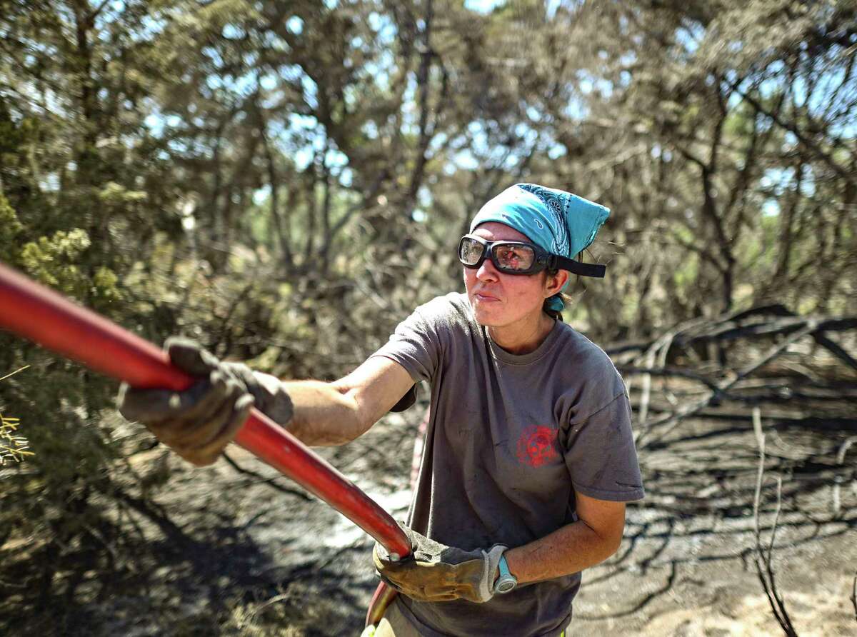 Firefighter Beth McMahon pulls a hose from her unit to battle the Big Sky Fire northwest of Fredericksburg, Texas, on Wednesday, Aug. 3, 2022. The fire, which was first reported on Tuesday at about noon, has burned about 1,400 acres. Fire crews from Gillespie, Kendall, Llano and other counties have contributed to the effort to put out the fire. The Texas A&M Forest Service has contributed its resources as well.