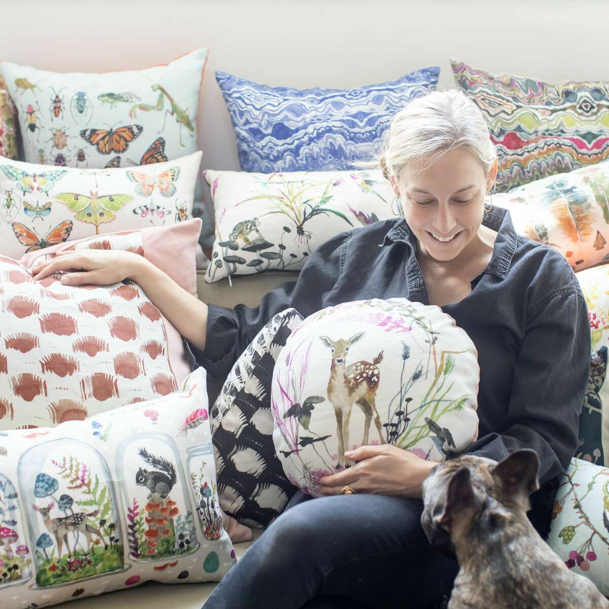 Artist and textile designer Betsy Olmsted with pillows made with fabrics featuring her nature-inspired designs.
