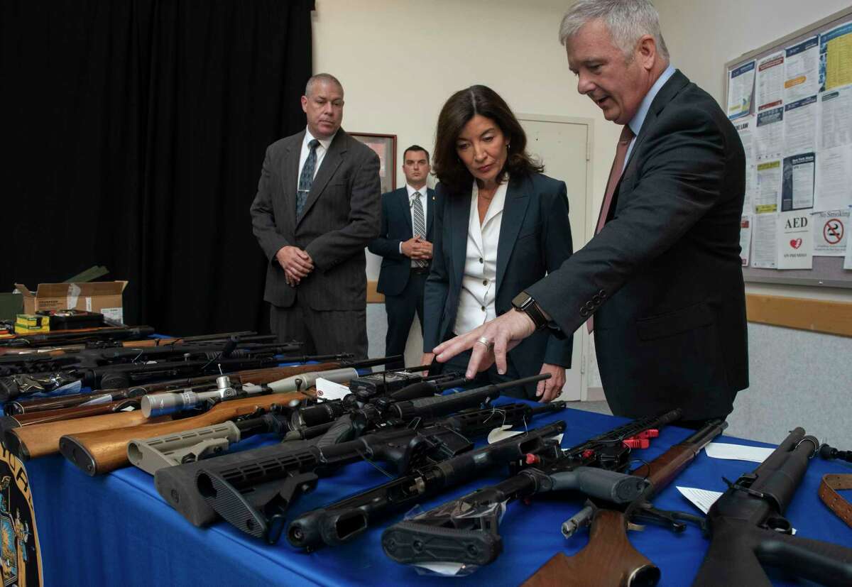 New York State Police Superintendent Kevin Bruen, right, shows Gov. Kathy Hochul seized guns before a press conference where she made an announcement about New York’s fight to stop the flow of illegal guns.