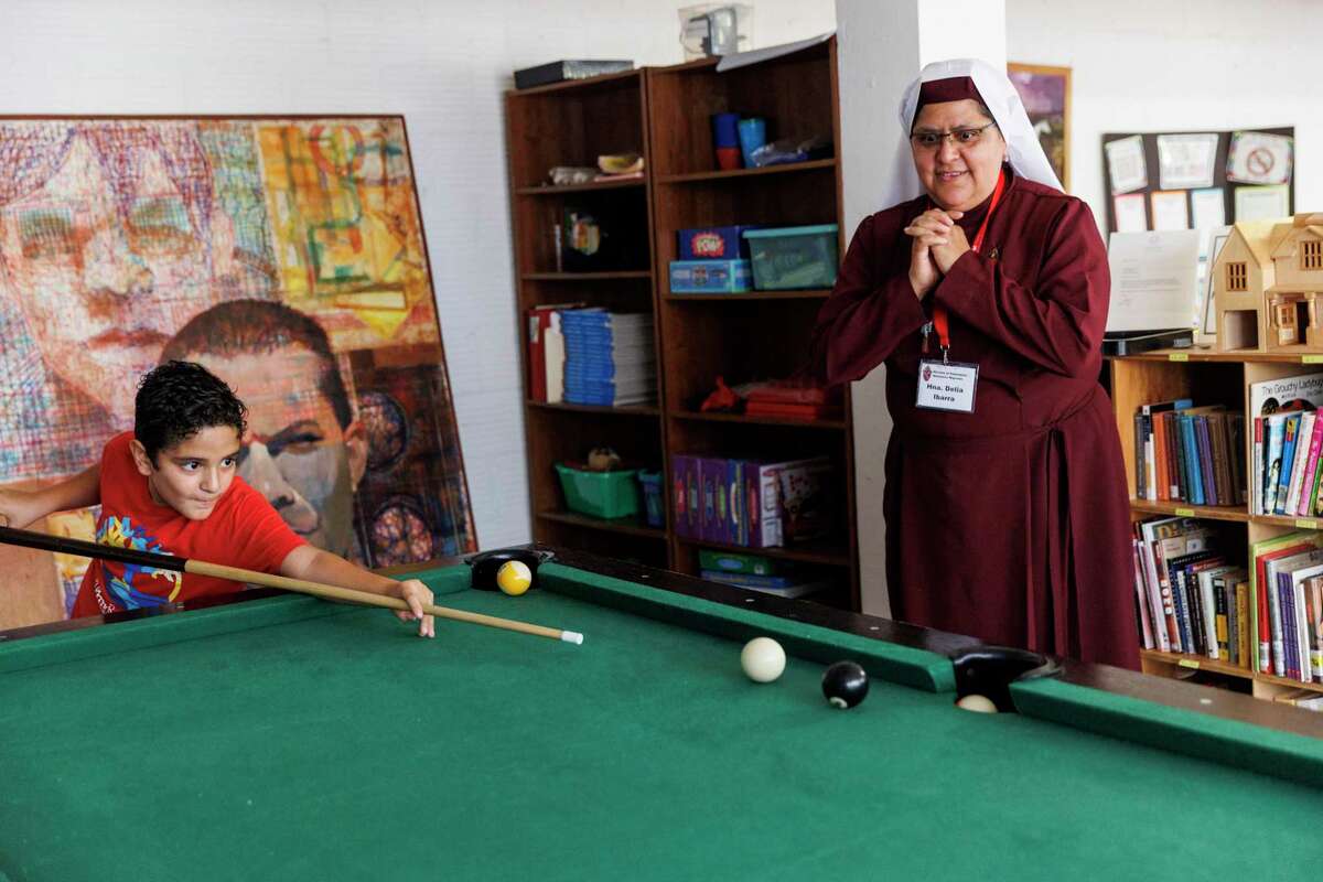 Sister Delia Aurora Ibarra Rodriguez of the Diocese of Kalamazoo, Mich., watches Remberto Tijerina attempt to sink the eight ball during a game of pool July 27, 2022, during Camp I CAN in Uvalde.
