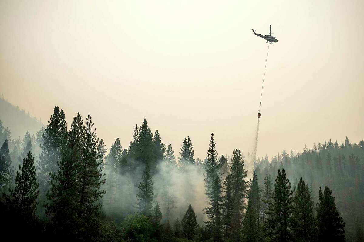 A helicopter drops water on a hot spot while battling the McKinney Fire on Tuesday, Aug. 2, 2022, in Klamath National Forest, Calif.