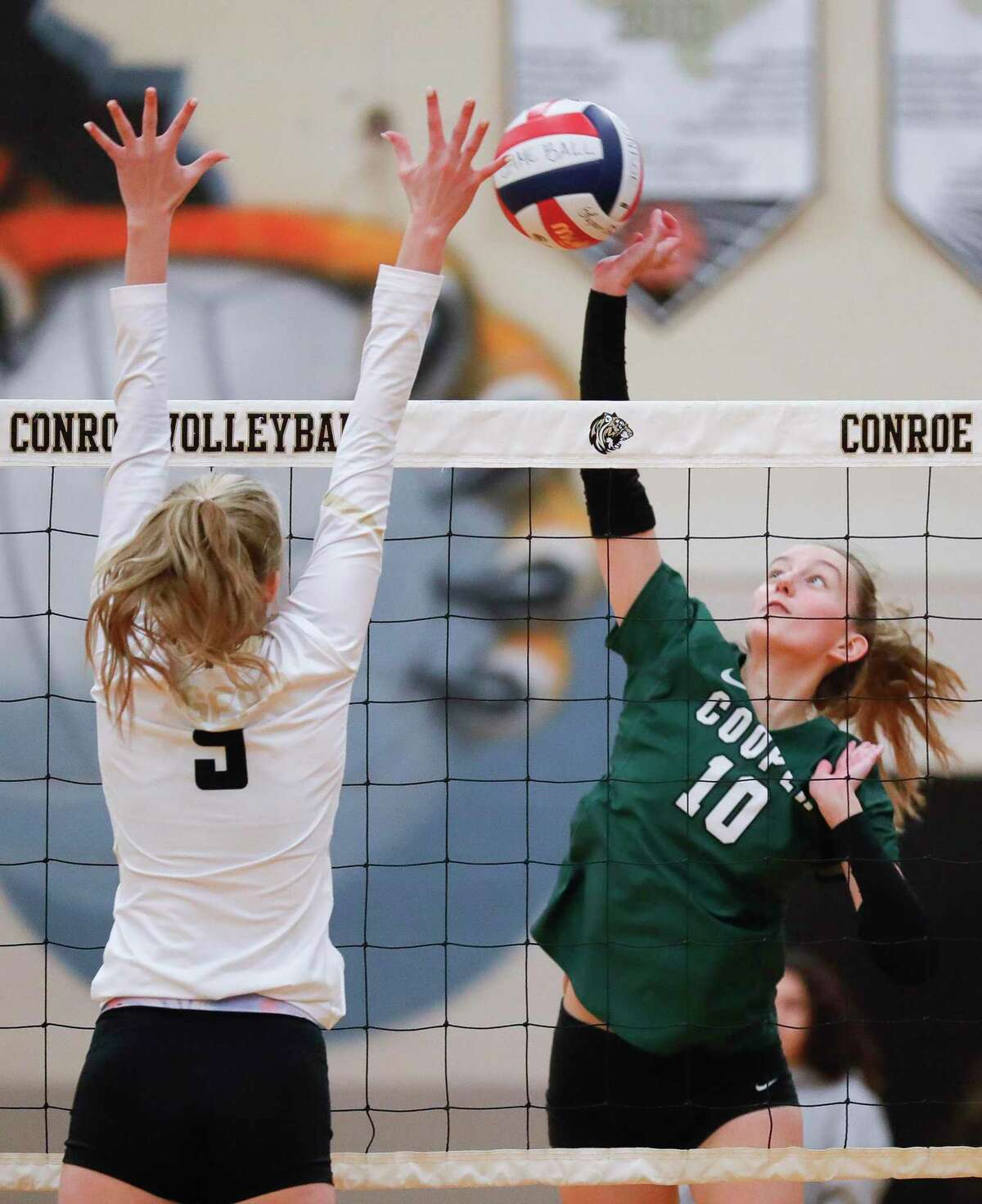 John Cooper outside hitter Rivers Kolesar (10) gets a shot past Conroe middle blocker Avery Sims (9) during the third set of a non-district high school volleyball match at Conroe High School, Wednesday, Sept. 15, 2021, in Conroe.