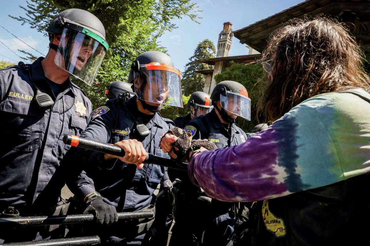 2022年8月3日，星期三，在加州伯克利，警察在抗议者和进入人民公园之间设置了一道屏障。抗议者聚集在一起，谴责为开发学生公寓而清理公园的行为。(Brontë Wittpenn/San Francisco Chronicle via AP)