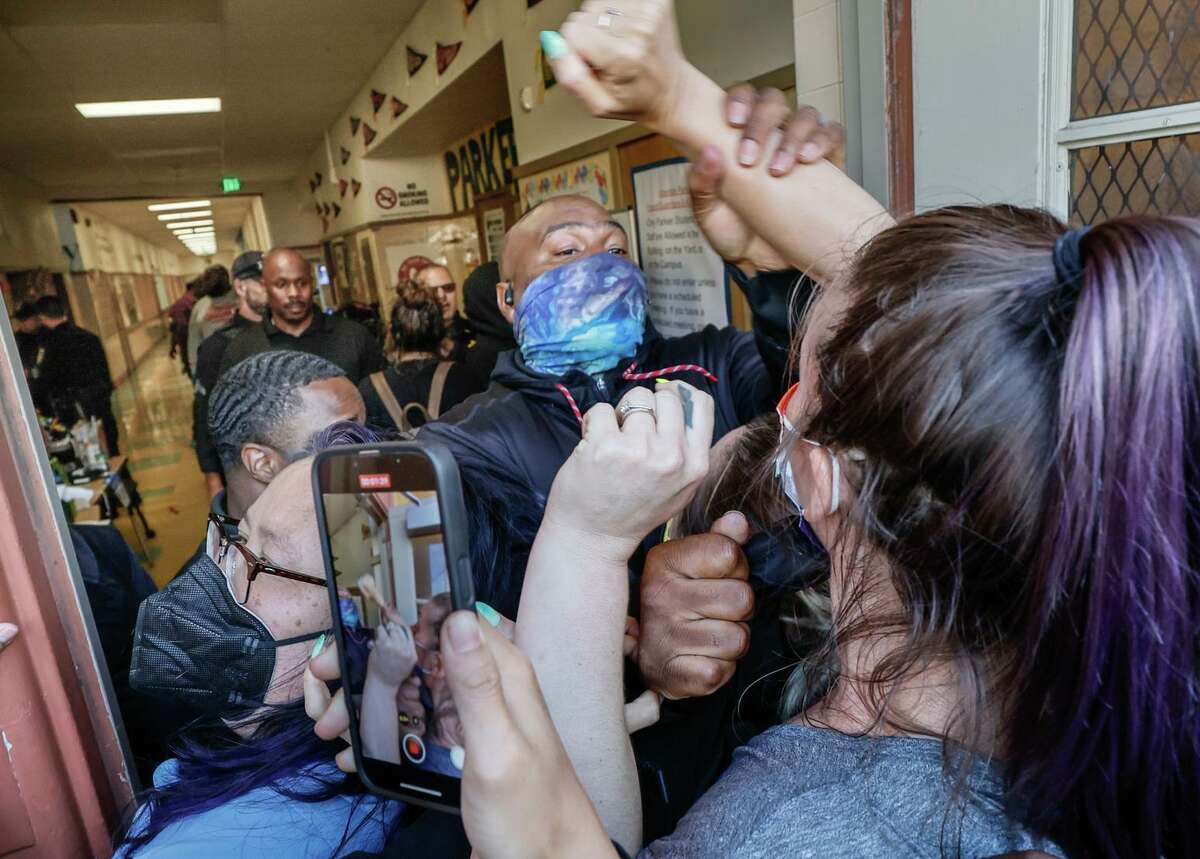 An Oakland Unified School District security guard tries to keep a crowd of people from forcing their way into Parker Elementary School in Oakland, Calif. on Thursday, Aug. 4, 2022.