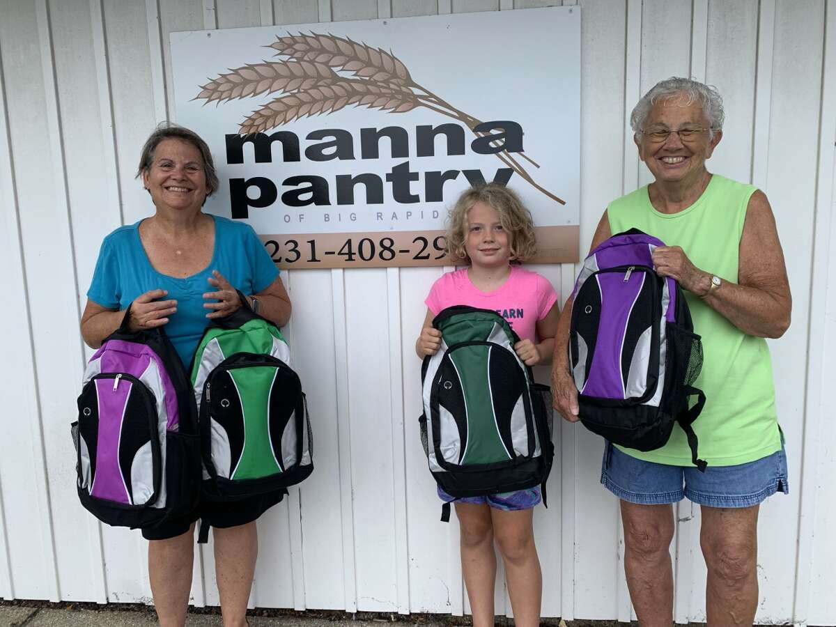 Manna Pantry volunteers fill backpacks for the back to school backpack giveaway. School supplies are free to clients with children in fifth through twelfth grade. Volunteers Annette LaRock (left), Morgan (center), and Sara Ham (right) help fill backpacks.  