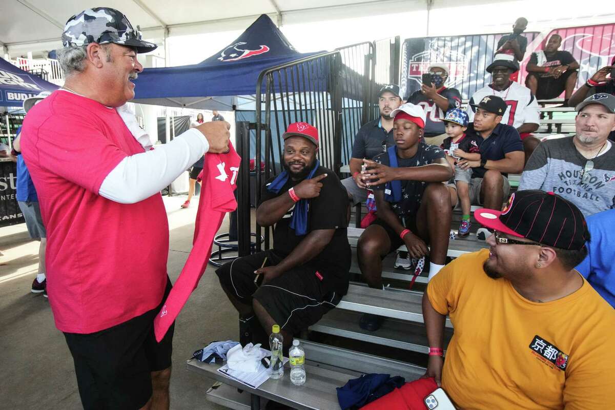 Houston Texans CEO Cal McNair hands out t-shirts to fans during an NFL training camp Friday, Aug. 5, 2022, in Houston.