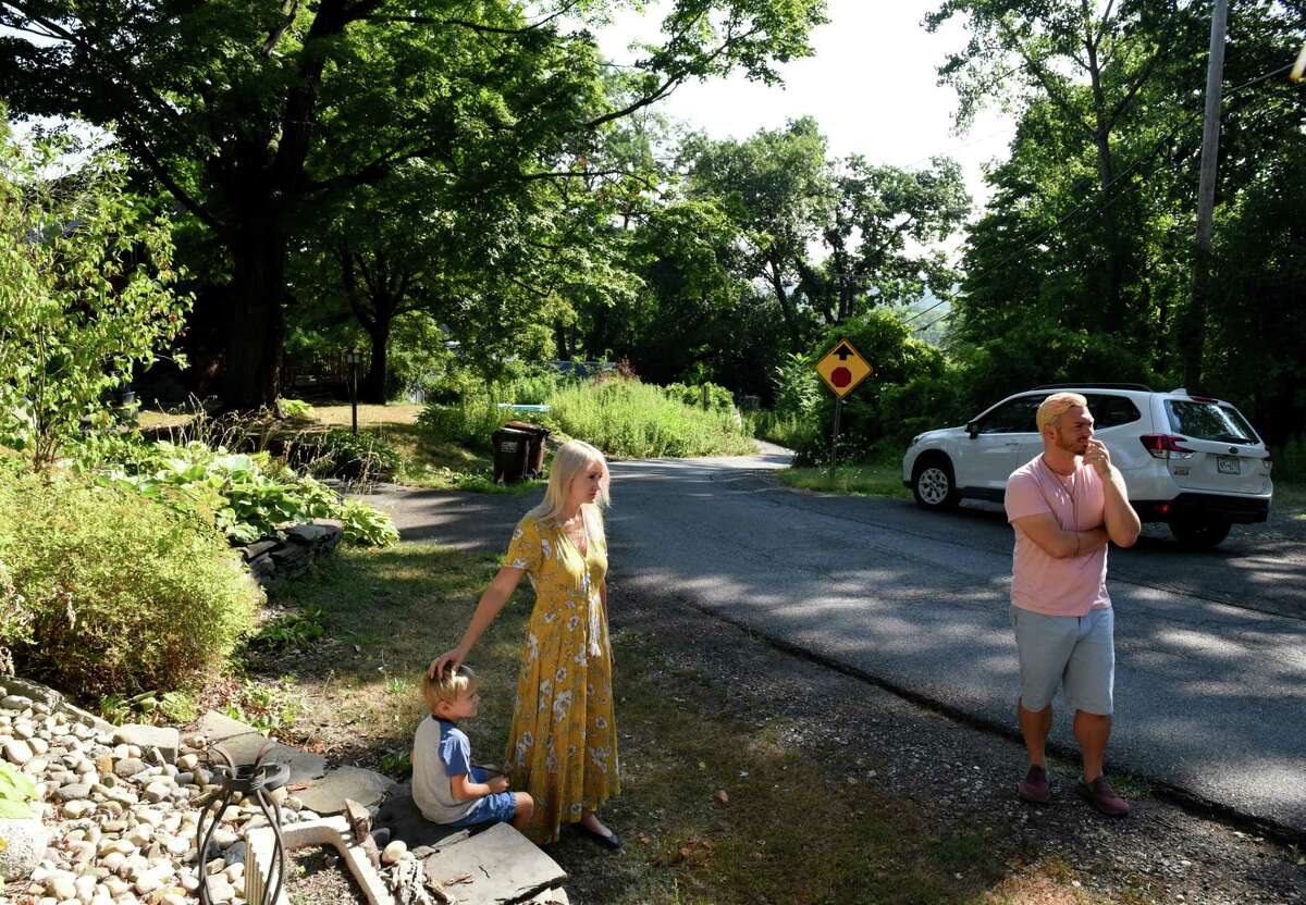 Anders Lane home owners Natasha Fiato with son Asher, 5, left, and Nathaniel Gray, right, stand on their street across from Beacon Island on Thursday, Aug. 4, 2022, in Glenmont, N.Y.