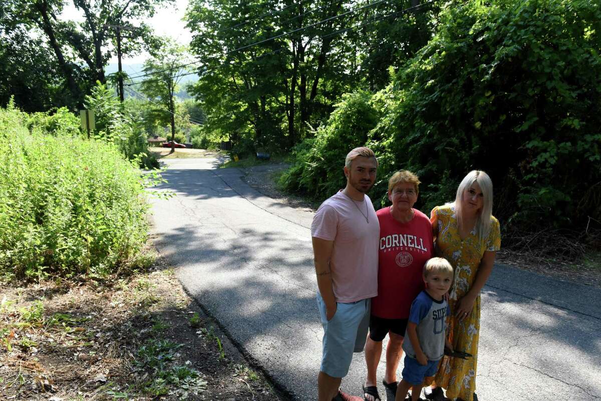 Anders Lane residents Nathaniel Gray, left, Joanne Maier, center, and and Natasha Fiato with son Asher, 5, right, stand on their street across from Beacon Island on Thursday, Aug. 4, 2022, in Glenmont, N.Y.