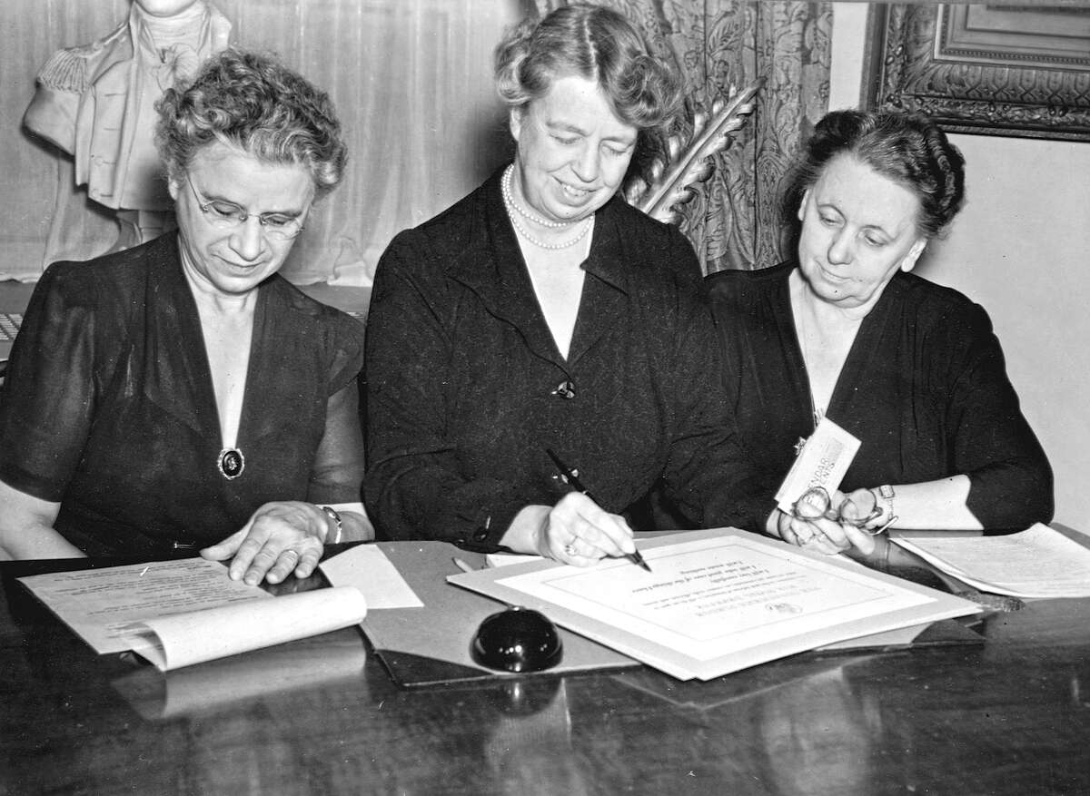 Henrietta Nesbitt (left), joins first lady Eleanor Roosevelt in signing a certificate in a White House office.