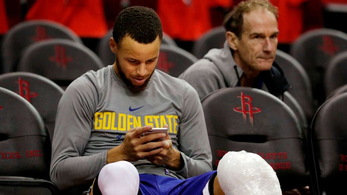 Steph Curry checks his phone at the 2018 conference finals.