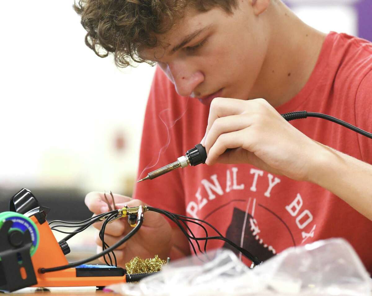 Rising sophomore Michael Sasser solders elements of a drone during a shop summer school class at Westhill High School in Stamford, Conn. Monday, July 25, 2022. Students are making a drone during the summer class, which is a gateway for the school system's "career pathways" program set to launch in the fall.