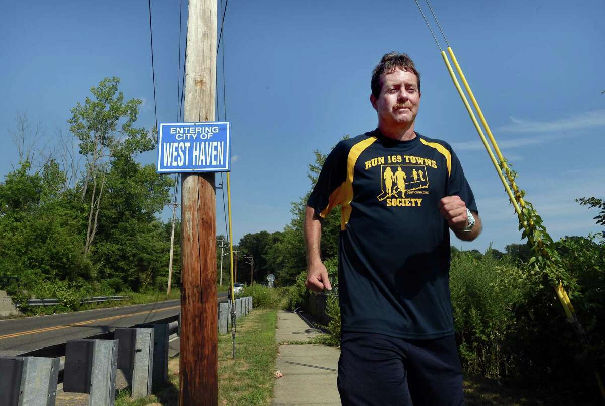 Brian Fidler, who has completed running a race in all 169 towns and cities in Connecticut, is photographed on Woodmont Road at the border between West Haven and Milford on Aug. 2, 2022.