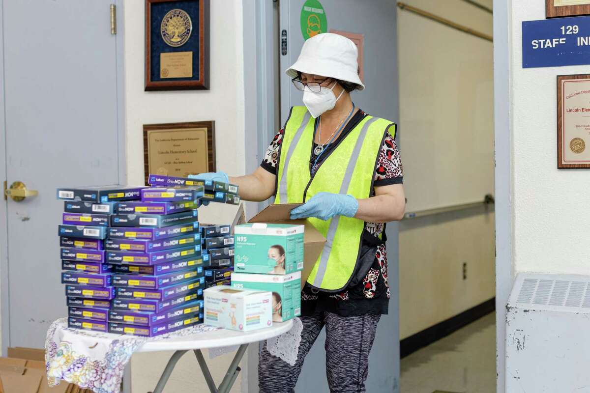 Chong Wang, staff at Lincoln Elementary School, unboxes COVID-19 rapid tests to give to students and parents on Friday, August 5, 2022, in Oakland, Calif.