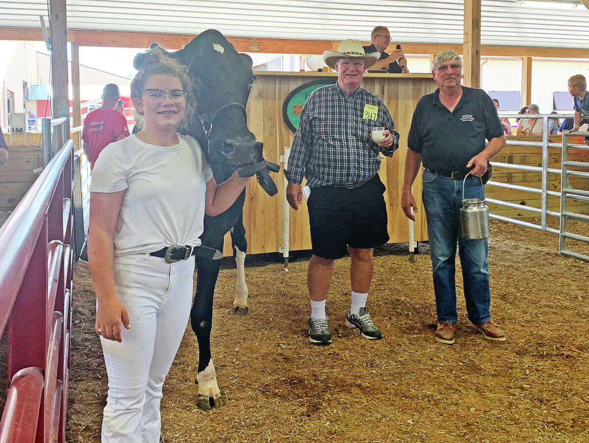 Gretchen Gentner, owner of the dairy cows awarded Grand Champion and Reserve Champion honors at the 2022 Huron Community Fair's Junior Livestock Sale, will donate a portion of the proceeds from the sale to the Shop with a Hero program.  Above, Emil Rummel Insurance Agency paid $2,200 for a gallon of milk from the Reserve Champion.