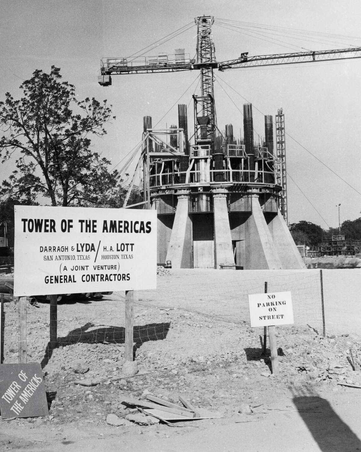 During the early stages of construction in 1966, wedge-shape concrete structures support the base of the future Tower of the Americas, with rebar and mechanical crane on top. Signs credit a “joint venture” of the general contractors, Lyda & Lott of San Antonio and H.A. Lott of Houston.