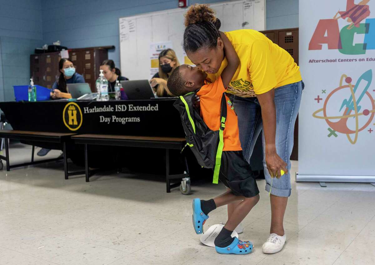 Isaiha Wishop, 5, hangs onto his grandmother, Cordelia Jackson, as he whispers in her ear during Saturday’s back-to-school bash at the Harlandale Alternative Center in San Antonio.