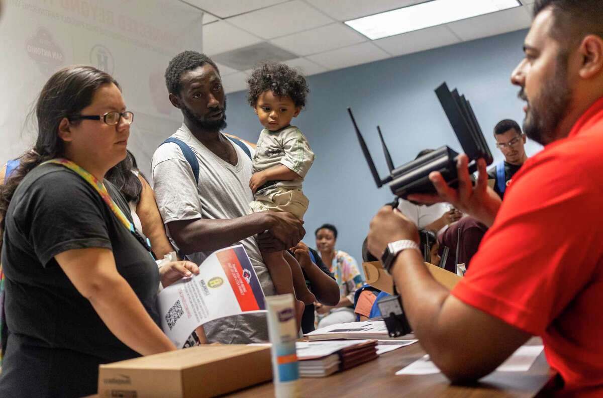 The Wedington family receives instructions on how to install an internet router at home during Saturday’s back-to-school bash at Harlandale Alternative Center.