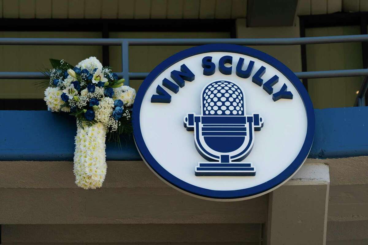 A bouquet of flowers sits next a plaque bearing the name of broadcaster Vin Scully at Dodger Stadium before a baseball game between the Los Angeles Dodgers and the San Diego Padres on Friday, Aug. 5, 2022, in Los Angeles. The Hall of Fame broadcaster died Tuesday night.