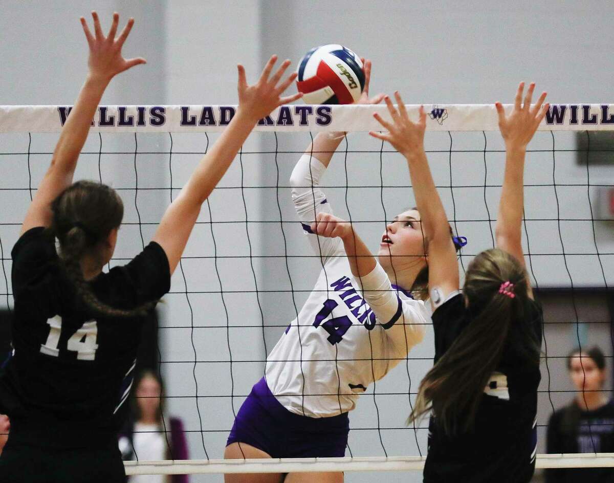 Willis’ Carly Paugh (14) gets a shot off against New Caney’s Mia Chapa (14) and Ava-Marie Miller (9) during the second set of a high school volleyball match at Willis High School, Tuesday, Sept. 7, 2021, in Willis.