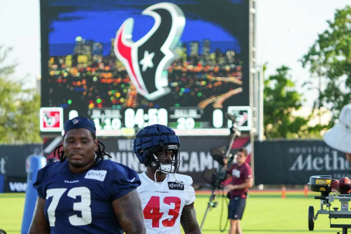 Houston Texans offensive lineman Tre'Vour Wallace-Simms (73) and linebacker Neville Hewitt (43) walk on the field during an NFL training camp Sunday, Aug. 7, 2022, in Houston.