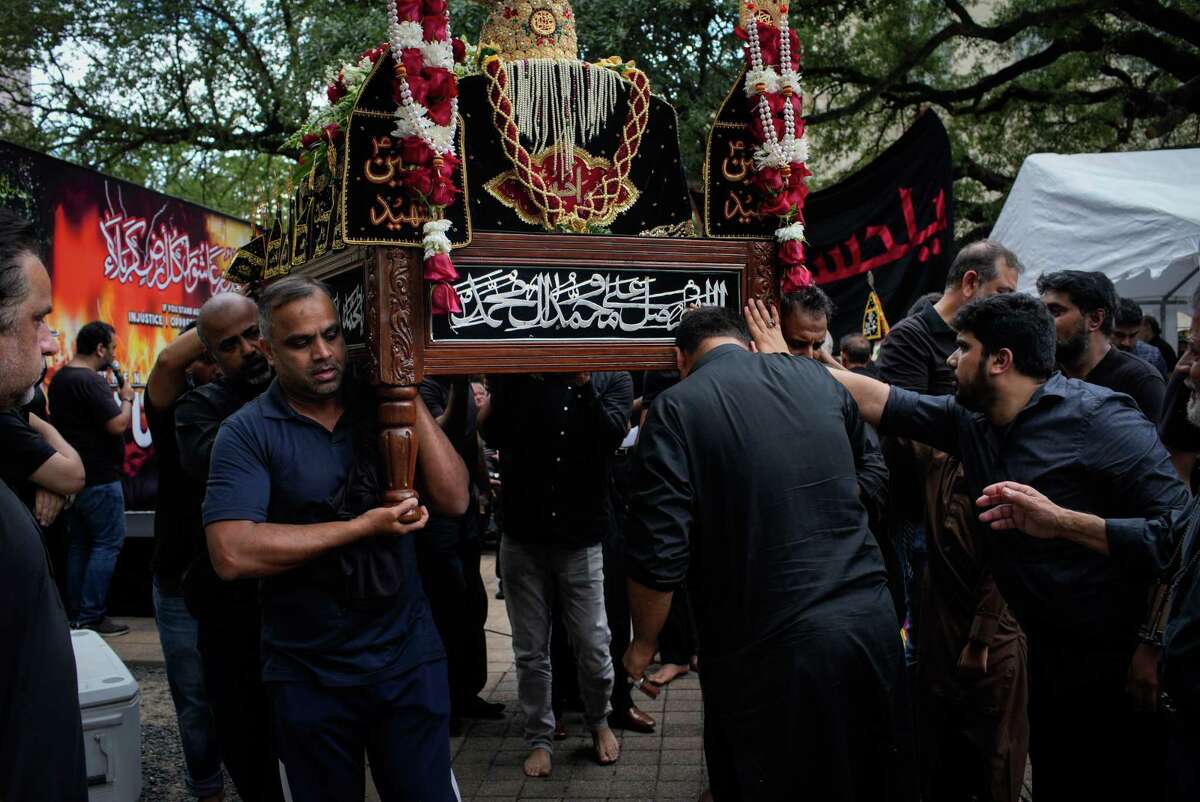 Men kiss and touch a coffin representing Imam Husayn ibn Ali during a commemorative procession Saturday, Aug. 6, 2022, in downtown Houston. Hundreds of Shiite Muslims gathered to remember Imam Husayn’s martyrdom around 1350 years ago with prayer, eulogies and a procession through downtown.