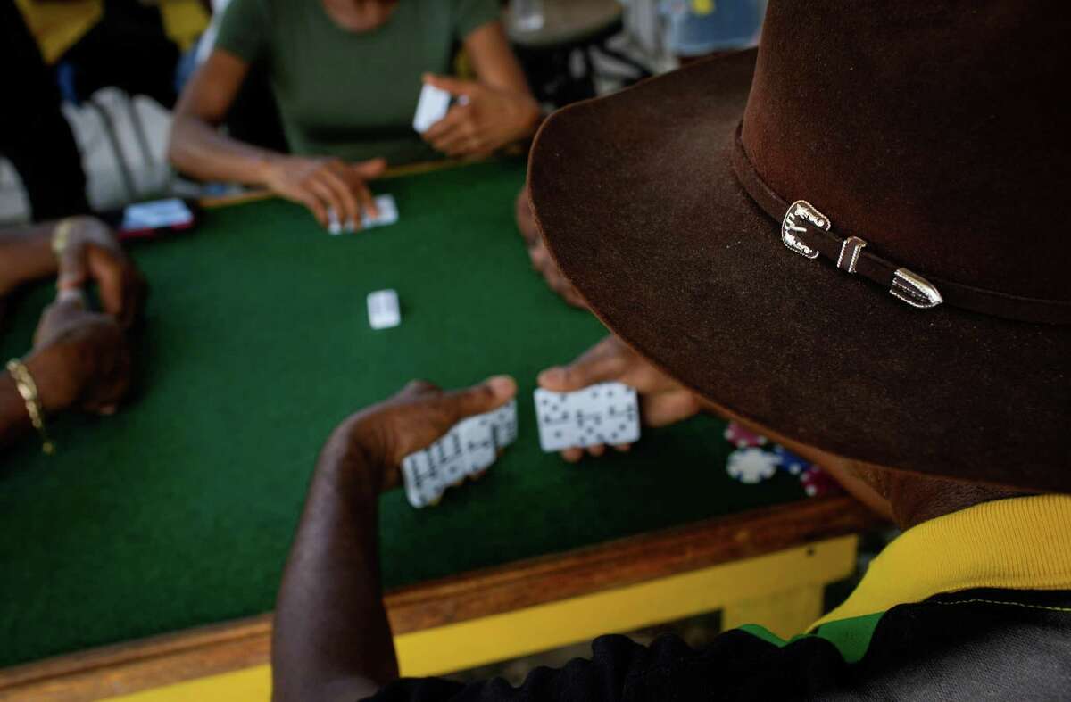 Adrian Eulette wears a cowboy hat as he plays dominoes Sunday, Aug. 7, 2022, at the Houston Missouri City Domino Club in Missouri City. Several dozen people gathered for a fundraiser celebrating the anniversary of Jamaican independence.