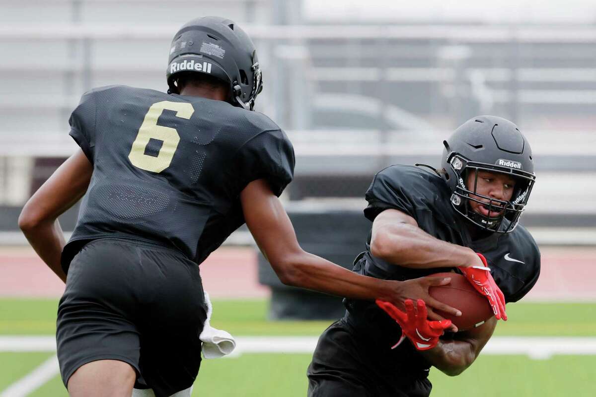 Cypress Park back Ryan Rasco, right, takes a hand off from quarterback Deyon Batiste, left, during a football practice at the campus stadium Friday, Aug. 5, 2022 in Cypress, TX.