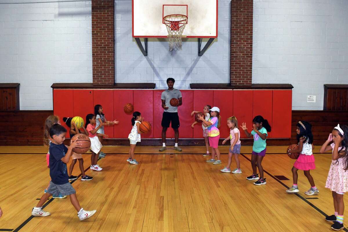 Forward Richie Springs of the University of Connecticut men’s basketball team works with summer campers during a visit to the Wakeman Boys & Girls Club, in Fairfield, Conn. Aug. 8, 2022.