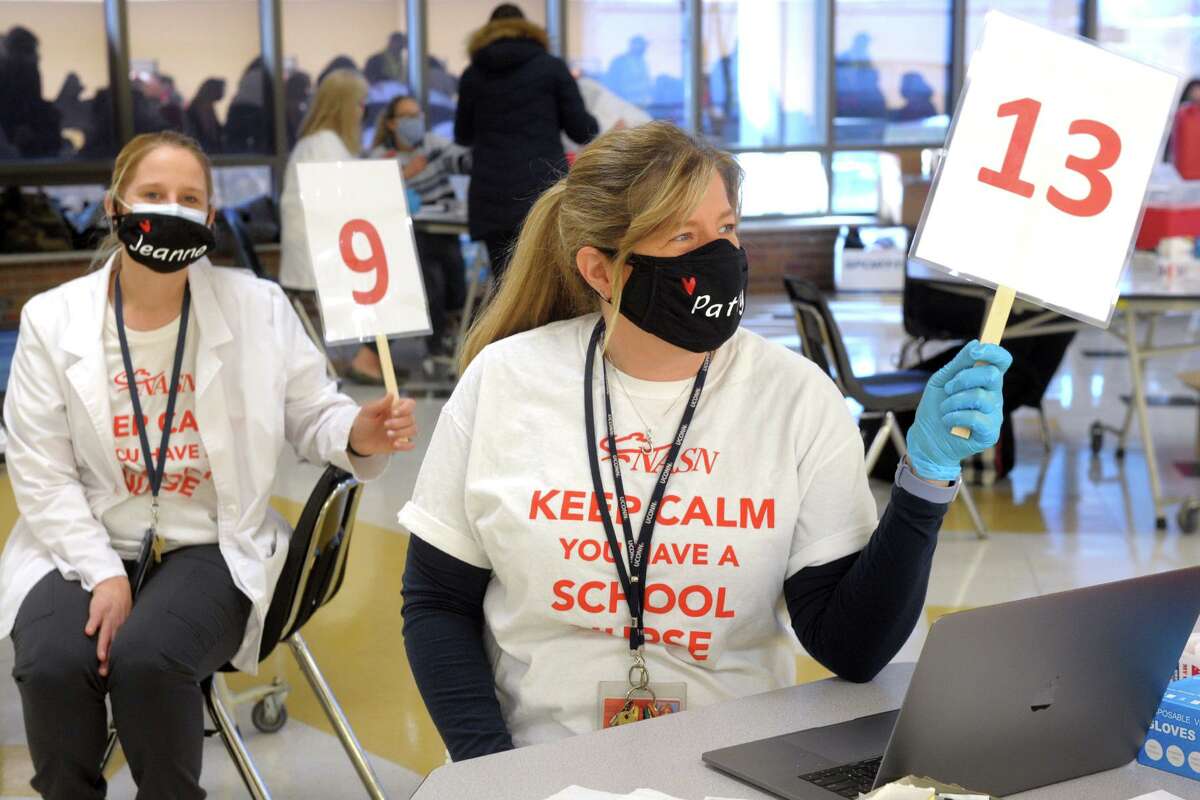 School nurses Patty Gold, right, from Madison Middle School, and Jeanne Hoggatt, from Middlebrook School, wait to give out COVID-19 vaccinations during the vaccination clinic held for teachers and school staff in Trumbull, Conn. March 4, 2021.