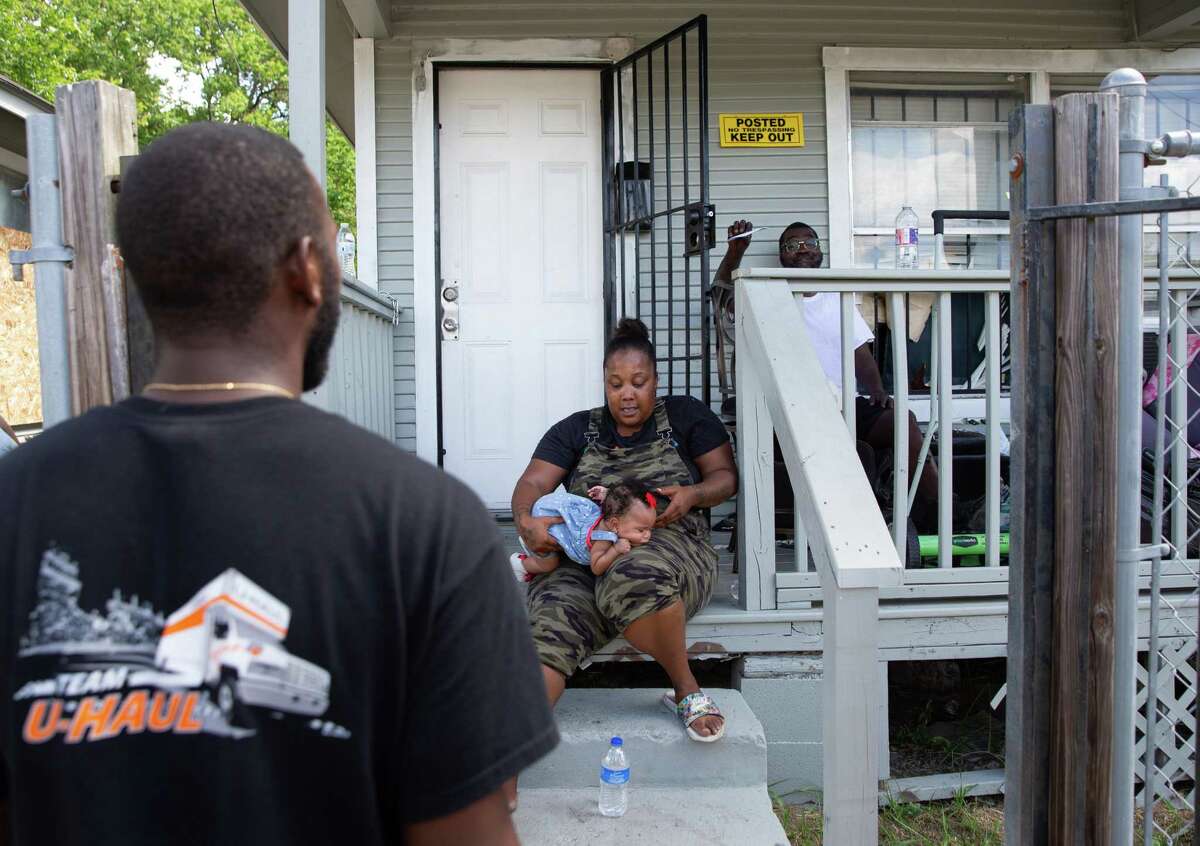 Anthony Hudson, back, who is locked out of his home by his landlord, tells a U-Haul truck driver that he is not going to move out of the house Monday, Aug. 8, 2022, in Houston. A landlord tried to evict tenants because she said she got a $11,000 water bill last month. Sitting in the front are his neighbors Terria Mathis and her 5-month-old daughter, Michelle Stewart.