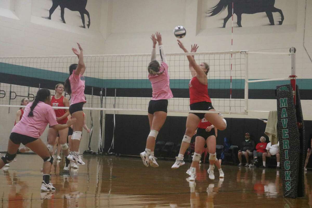 A Huffman player bids to elude the block attempts by the Lady Mavs along the net in Friday's scrimmage.