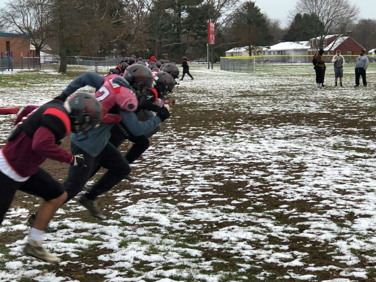 The Cromwell/Portland football team goes through its paces in the snow and mud on its practice field, just two days before the 2021 Class S championship game.