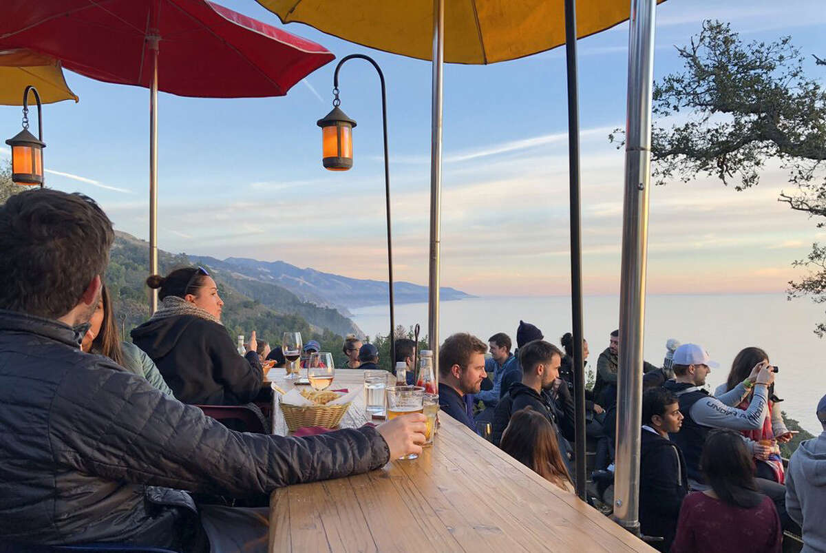 On a busy afternoon, visitors to Big Sur's Nepenthe enjoy the sun setting over the Pacific accompanied with some food or a cool beverage. 